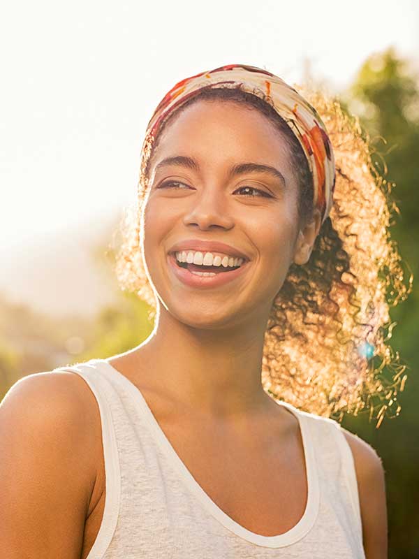 Beautiful woman smiling at park during sunset.